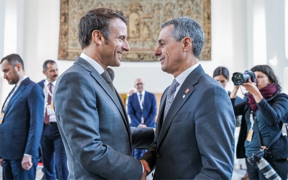 Le président de la Confédération Cassis et le président français Emmanuel Macron se font face et se parlent.