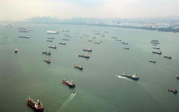 Cargo ships in the port of Singapore sailing in the same direction. 