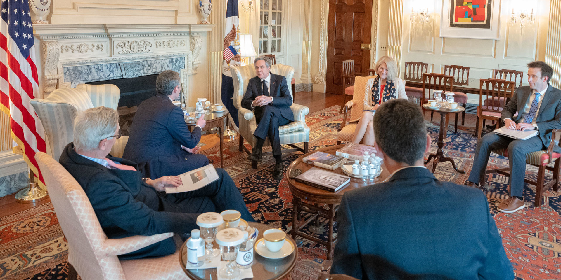 Six people sitting in a circle around a small wooden table, including Federal Councillor Ignazio Cassis talking to US Secretary of State Anthony Blinken.