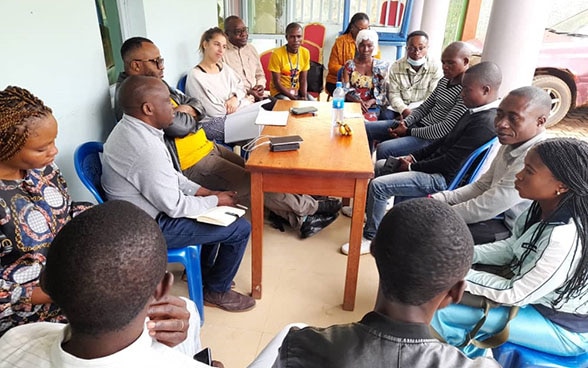  Un groupe de personnes discutent en République démocratique du , assises autour d’une table.