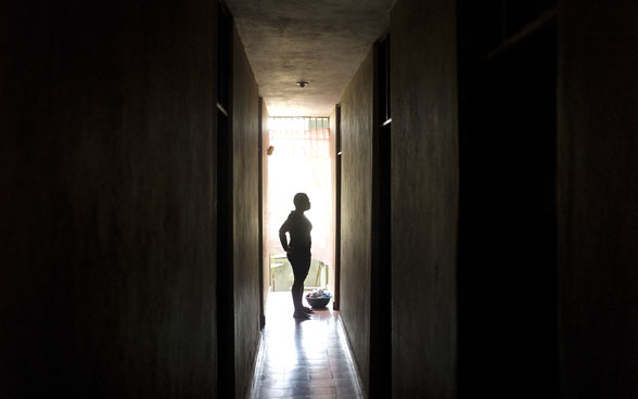 Une femme apparaît à contrejour au fond d’un couloir.