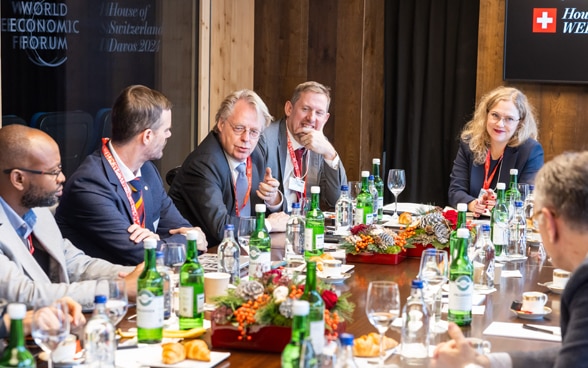 Katarina Frey von der Abteilung Digitalisierung des EDA sitzt mit mehreren anderen Personen an einem Tisch bei der Lancierung der ICAIN-Initiative im Rahmen des WEF in Davos.