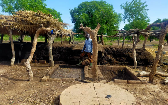 A farmer from Burkina Faso stands next to a compost heap.