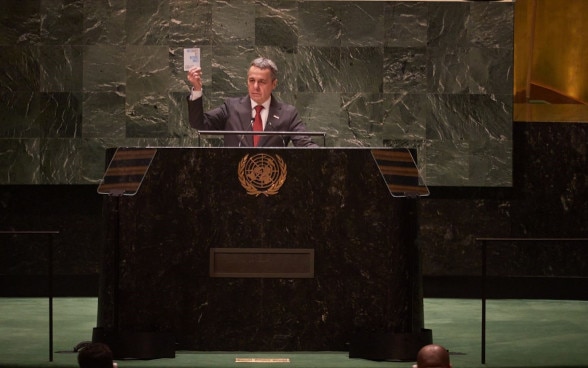 Ignazio Cassis at the podium of the United Nations General Assembly in New York. He holds a copy of the UN Charter in his hand.