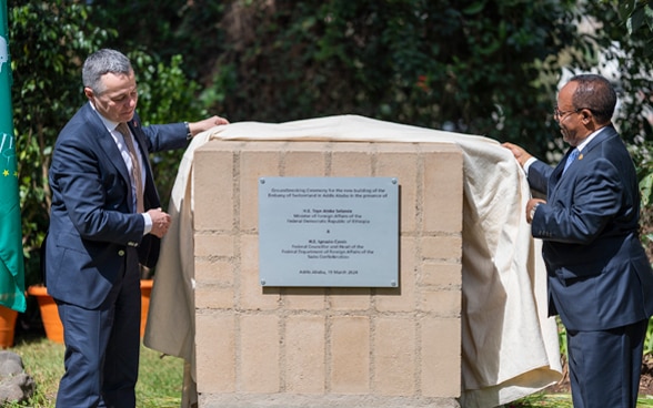 Ignazio Cassis et Taye Atske Selassie enlève un drap d’une pierre sur laquelle est apposée une plaque en métal.