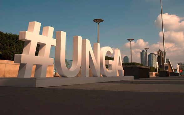 Man-sized lettering elements Hashtag UNGA stand in front of the New York skyline.