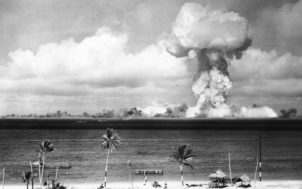 Viewed from a neighbouring Pacific island, a huge mushroom cloud expands on the horizon following a nuclear test on Bikini Atoll.