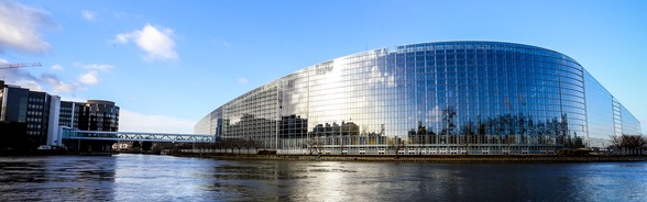 The European Parliament building in Strasbourg with the river reflected in the glass facade.