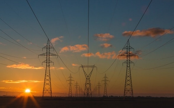 Una serie di linee ad alta tensione al tramonto