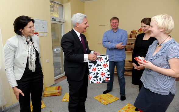 Der Schweizer Botschafter übergibt den Besitzern des Kindergarten POGA zur Feier des 1‘000. Mikrokredits kleine Präsente.