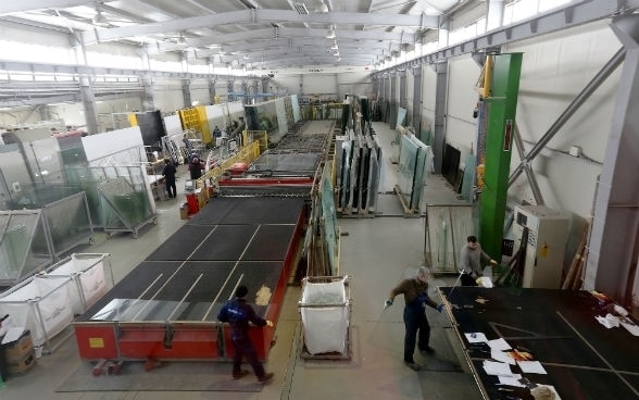 Männer arbeiten in der Fabrikhalle eines Fensterproduzenten.