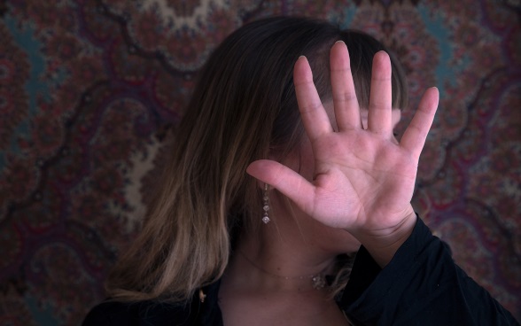 A trafficking victim conceals her face with her hand.