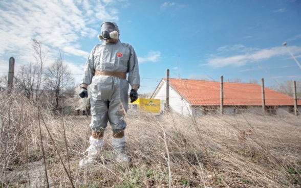 Man in protective clothing standing in front of a warehouse.
