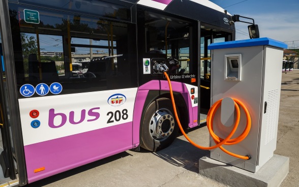 Un bus électrique arrive à un arrêt, où plusieurs personnes attendent.