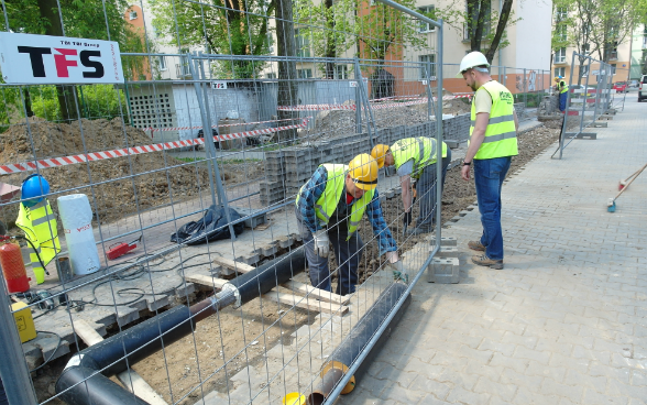 Construction site with three workers and pipes