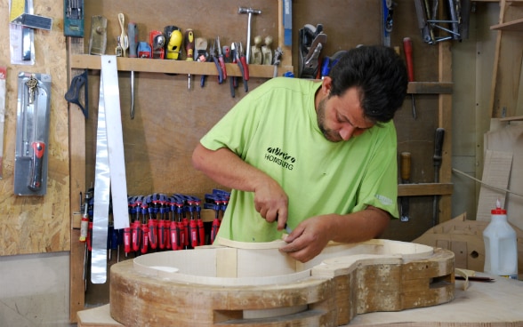 Un artigiano costruisce un violoncello