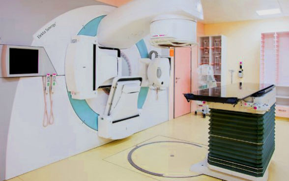 Photo représentant un appareil de radiothérapie, dans une salle d’hôpital.