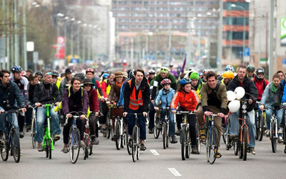 A crowd of cyclists completely fills a city street.