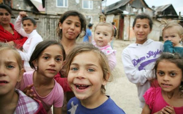 Neun Kinder und eine Frau blicken in die Kamera.