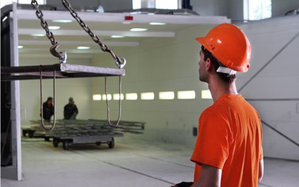 A young man wearing a hard hat standing inside an industrial building site.