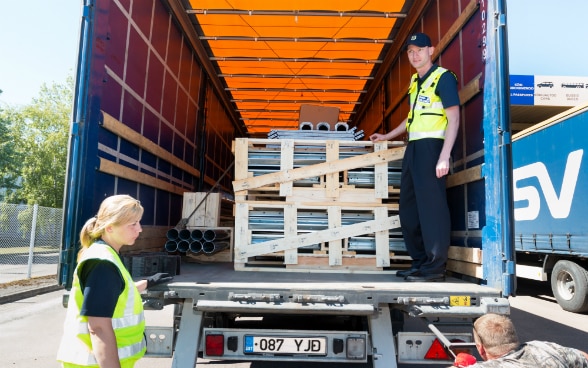 Two officials checking the load inside a lorry.