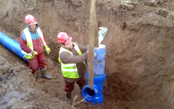Two men positioning a new water pipeline.