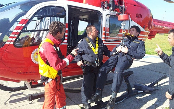 Three men simulate a rescue mission on a REGA helicopter.