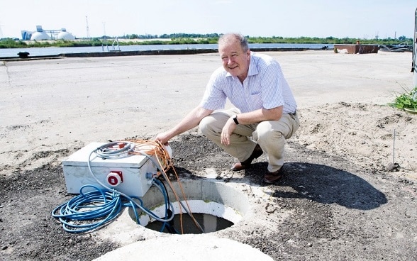 A man crouches next to a maintenance shaft in the contaminated port.